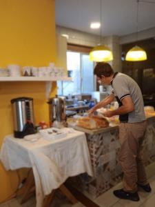 un hombre de pie en una cocina preparando comida en BC Paradise Hostel & Suítes, en Balneário Camboriú