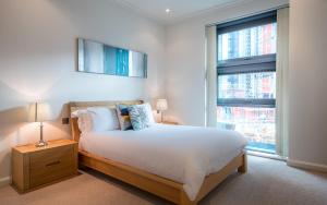 um quarto com uma cama grande e 2 janelas em NY-LON Corporate Apartments em Londres
