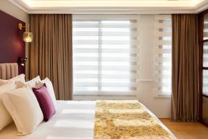 a bedroom with a bed with purple and white pillows at The Excelsior - Small Luxury Hotels of the World in Thessaloniki