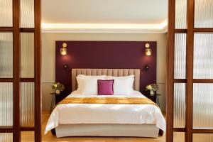 a bedroom with a large bed with a purple headboard at The Excelsior - Small Luxury Hotels of the World in Thessaloniki