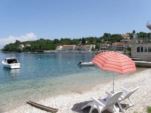 a beach with two chairs and an umbrella and a boat at Apartments Korta in Račišće