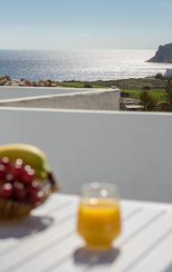 a glass of orange juice and a basket of fruit on a table at Sarantis apartments in Provatas