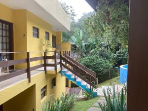 a yellow building with stairs leading to a yard at Suíte na Vermelhinha do Tenório in Ubatuba