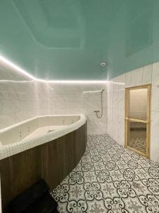 ein Bad mit einer Badewanne und Fliesenboden in der Unterkunft Апартаменти Underground&SPA in Lwiw