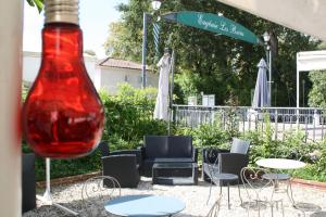 czerwony wazon stojący obok grupy krzeseł i stołów w obiekcie Hôtel Chez Léonie - Chez Mamie Canne w mieście Eugénie-les-Bains