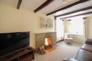 a living room with a television and a fireplace at Sunny Corner Cottage in Hayle