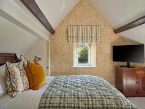 a bedroom with a bed and a tv and a window at Ellenborough Park in Cheltenham