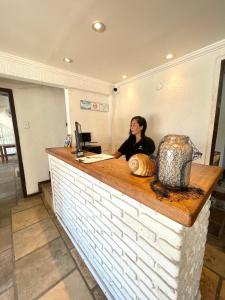 a woman sitting at a counter at a restaurant at Orlanova Hotel in Arraial do Cabo