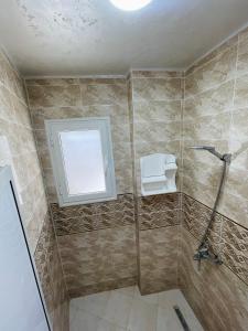 a bathroom with a shower with a toilet and a window at Seaside Guest House in Ghār al Milḩ