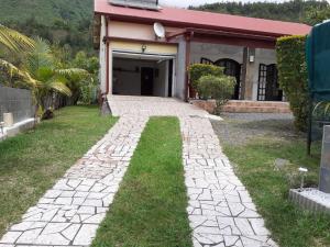 a stone walkway leading to a house with a garage at Charmante maison au cœur des 3 montagnes in Salazie