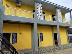 a yellow and white building with a balcony at Tingang84 Guesthouse in Palangkaraya