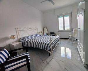 a white bedroom with a bed and a chair at La Brezza Marina in Fezzano
