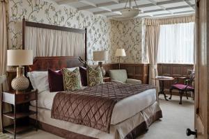 a hotel room with a large bed and a chair at Ellenborough Park in Cheltenham