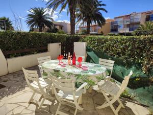 stół z krzesłami i kieliszki do wina na patio w obiekcie AQUAPLAGE Joli appartement RDC piscine 1 ère ligne mer Richelieu Cap d'Agde w Cap d'Agde