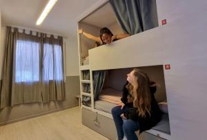 two girls sitting on top of a bunk bed at Onefam Ramblas in Barcelona