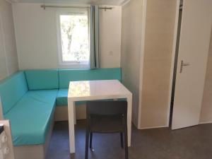 Vero的住宿－Camping Les Eaux Vives，一间设有蓝色沙发、桌子和窗户的客房