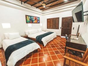 a room with two beds and a desk and a television at Casona Montanesa Quindío eje cafetero in Montenegro