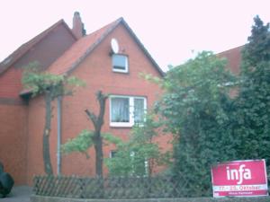 ein rotes Backsteinhaus mit einem Schild davor in der Unterkunft Guest House Schneider in Laatzen