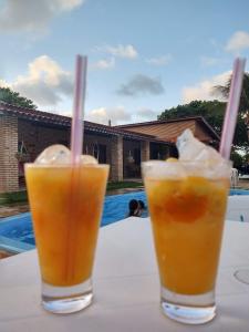 dos bebidas sentadas en una mesa junto a una piscina en Pousada Solar das Fontes en Beberibe