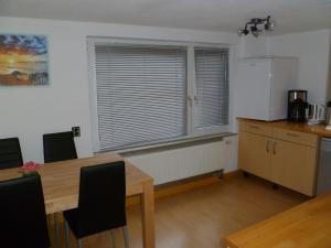 eine Küche mit einem Tisch, einem Kühlschrank und einem Fenster in der Unterkunft Guest House Schneider in Laatzen