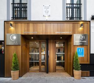 une entrée pour un immeuble de bureaux avec deux arbres en pot devant dans l'établissement nQn Aparts & Suites Sevilla, à Séville