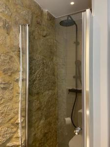 a bathroom with a shower with a stone wall at Casa Posto da Guarda Fiscal in Melgaço