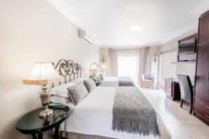 two beds in a white bedroom with a table at Adato Guesthouse in Potchefstroom
