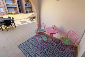 een roze tafel en stoelen op een tapijt op een patio bij Super logement au centre-ville in Acqui Terme