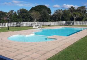 einen Pool in einem Garten mit einem weißen Zaun in der Unterkunft Studio 37 @ The Dunes in Plettenberg Bay