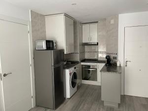 a kitchen with a refrigerator and a microwave at Apartamento Playa San Lorenzo Garaje opcional in Gijón