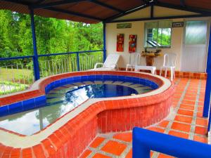 a pool in a house with a red and blue brick wall at Hotel Campestre El Refugio de Balsora in Filandia
