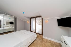 a white bedroom with a large bed and a flat screen tv at Gorgeous Flat with Sea View Jacuzzi in Antalya Kas in Kas