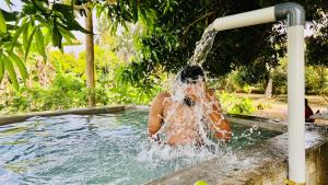 a person in a swimming pool under a water fountain at SERENE Stays - Kjsb farmhouse THANJAVUR in Thanjāvūr
