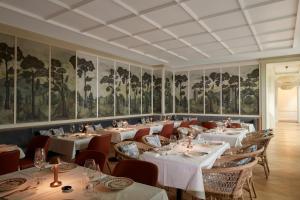 a dining room with tables and chairs and paintings on the walls at Maison Delano Paris in Paris