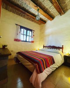 Un dormitorio con una cama con una manta de colores. en Hostería Plaza Chica Tilcara en Tilcara