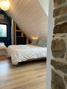 een slaapkamer met een bed en een stenen muur bij Gîte de l'Archipel in Trélévern