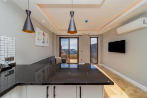 a kitchen with a black counter top and some lights at Sea and Nature View Cozy Flat with Pool in Kas in Kas