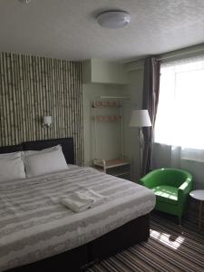 1 dormitorio con 1 cama y 1 silla verde en Tregonholme Hotel, en Bournemouth