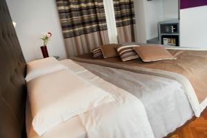 ein Bett mit weißen und braunen Kissen darauf in der Unterkunft Relais Forus Inn in Rom