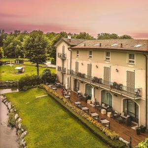 ein großes Gebäude mit einer Terrasse neben einem Fluss in der Unterkunft Hotel Il Corazziere in Merone