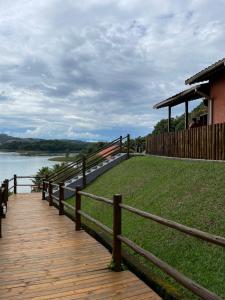 a wooden boardwalk next to a river with a fence at Chalé das Águas in Igaratá
