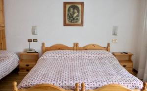 una camera con letto in legno e 2 comodini di Albergo Piani di Luzza a Forni Avoltri