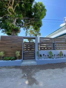 une clôture avec un arbre devant un bâtiment dans l'établissement Cozy Grace Place, à Orani