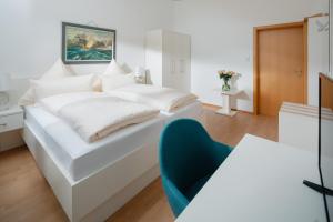 a white bedroom with a bed and a blue chair at Hotel am Denkmal Norderney in Norderney