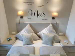 een bed met twee kussens en een bord met meoser bij Apartment 76 im Haus Villa Anna II in Sankt Peter-Ording