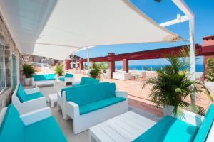 a patio with blue and white furniture and the ocean at Mogan Princess & Beach Club in Taurito