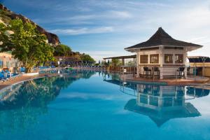 a pool at a resort with a building in the water at Mogan Princess & Beach Club in Taurito