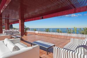 a patio with white chairs and tables and the ocean at Mogan Princess & Beach Club in Taurito