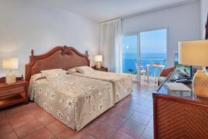 a bedroom with a bed and a view of the ocean at Mogan Princess & Beach Club in Taurito