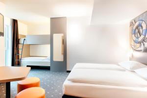 ein Hotelzimmer mit 2 Betten, einem Tisch und Stühlen in der Unterkunft B&B Hotel Emden in Emden
